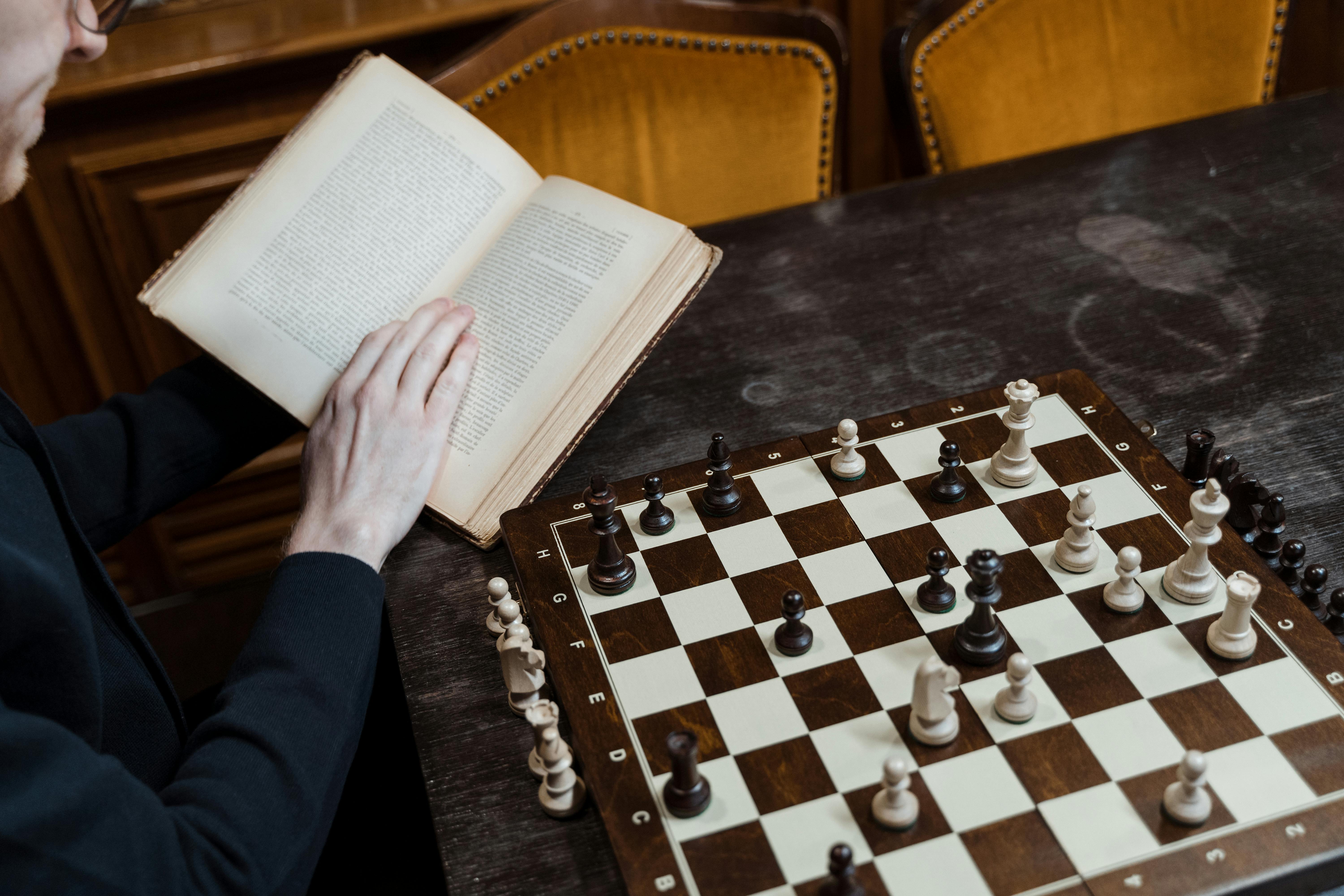 image of a person reading a book next to a chess board